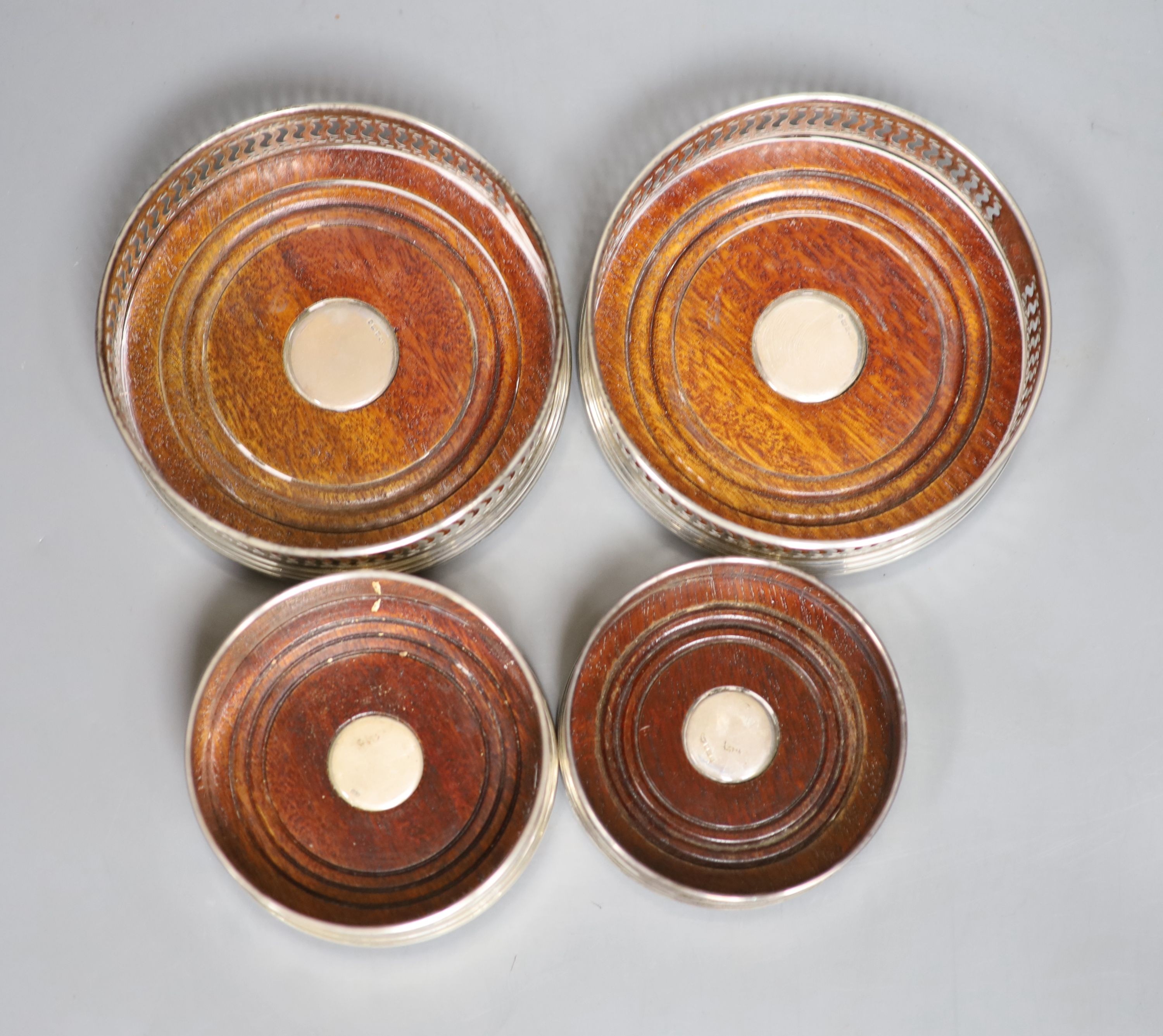 Four assorted modern silver mounted wine coasters, largest diameter 12.2cm.